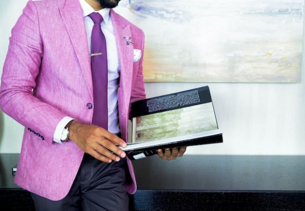 Man in pink suit holding a book