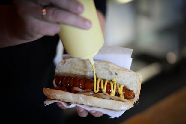 A person preparing hotdog sandwich