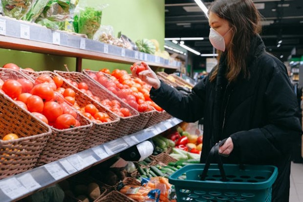 Woman holding a tomato in the grocery