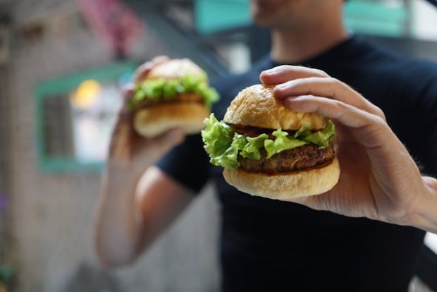 A person holding two burgers
