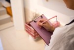 A woman writing on a pink paper