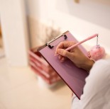A woman writing on a pink paper